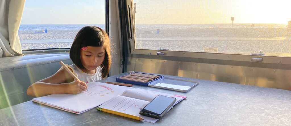 Student in an airstream on the beach working on Oak Meadow school