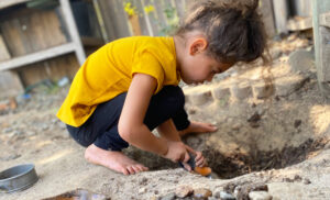 Student digging a hole in the backyard playing outside
