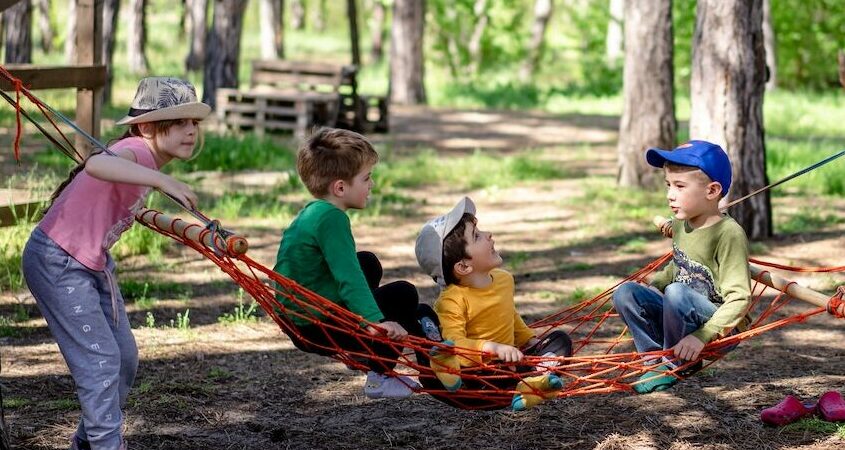 four kids playing outside on a hammock