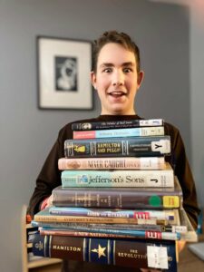 Oak Meadow student holding a huge pile of homeschool materials