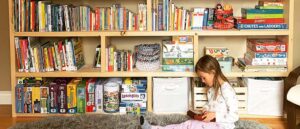 Oak meadow student sitting in front of a well organized bookshelf