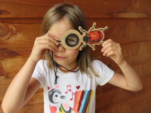 Young girl looking through a magnifying glass shaped like a ladybug