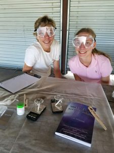 Two budding scientists wearing safety goggles and doing experiment