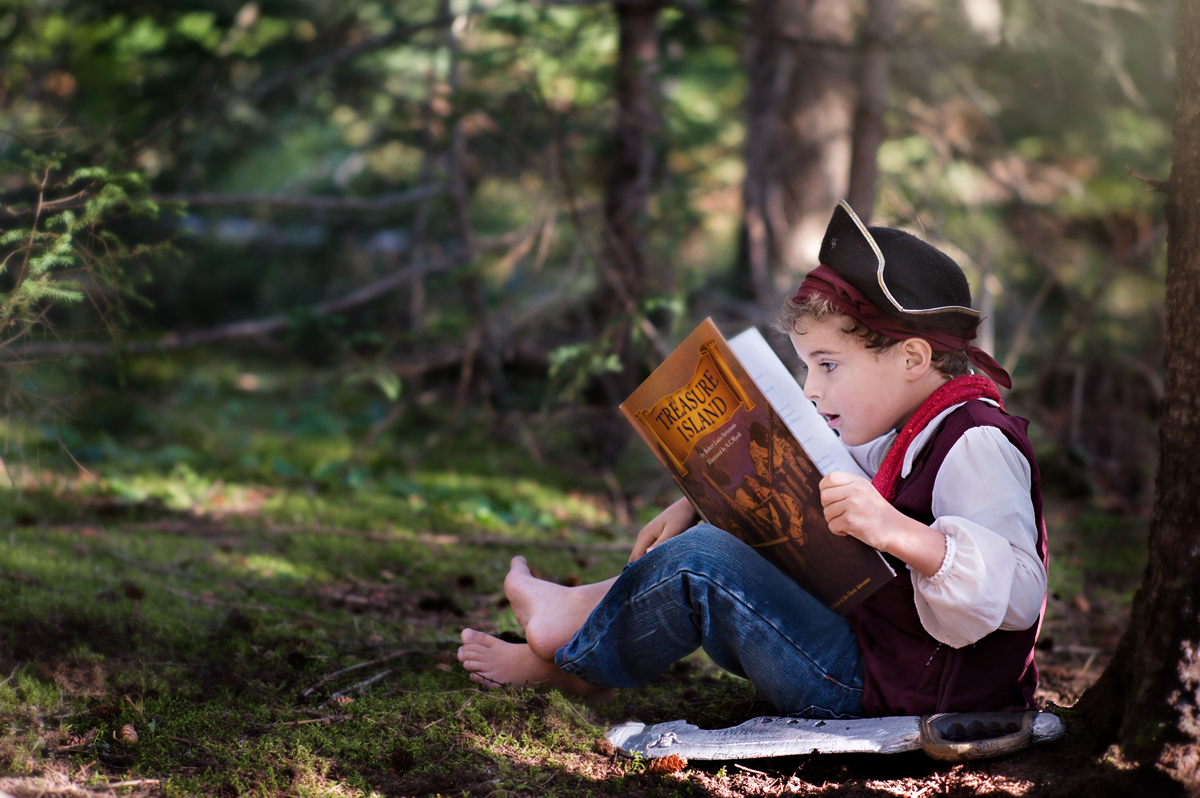 boy in a pirate costume reading a picture book