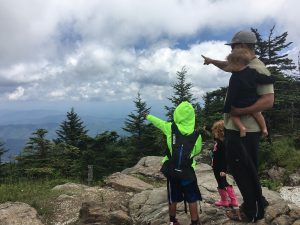 homeschool family looking at view from on top a mountain