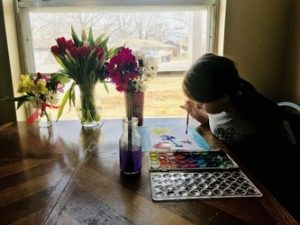 homeschooler painting by window with flowers