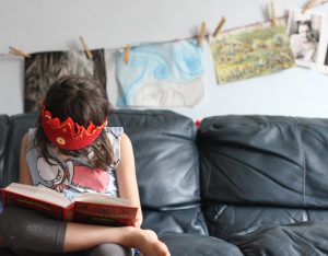 Oak Meadow Student reading and wearing homemade crown