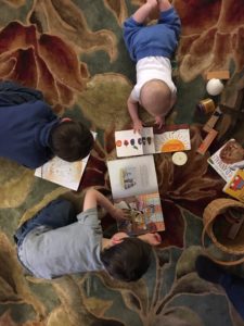 Three young children reading on floor