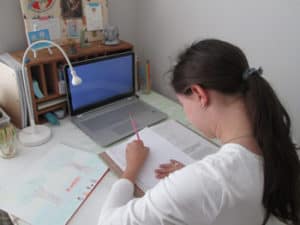 High School student working at their desk on homework with a laptop computer open