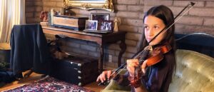 student practicing violin in their living room