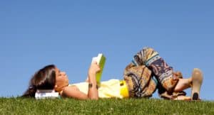 Oak Meadow student lying on the grass reading a book