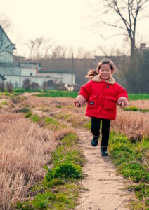 Oak Meadow homeschool student running in red jacket