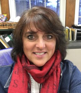 Headshot of Lori Humiston, Oak Meadow Middle School Teacher. Lori has brown hair and bangs and is wearing a red scarf with a blue jacket.