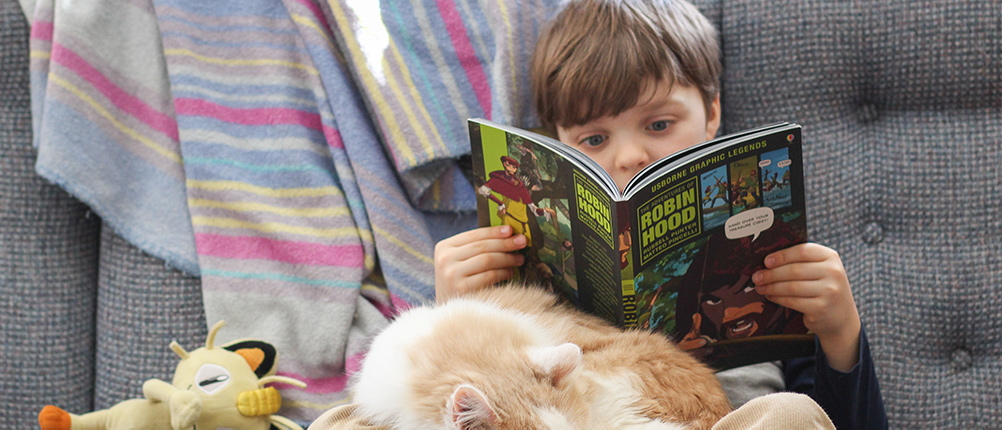 student reading with a cat in his lap