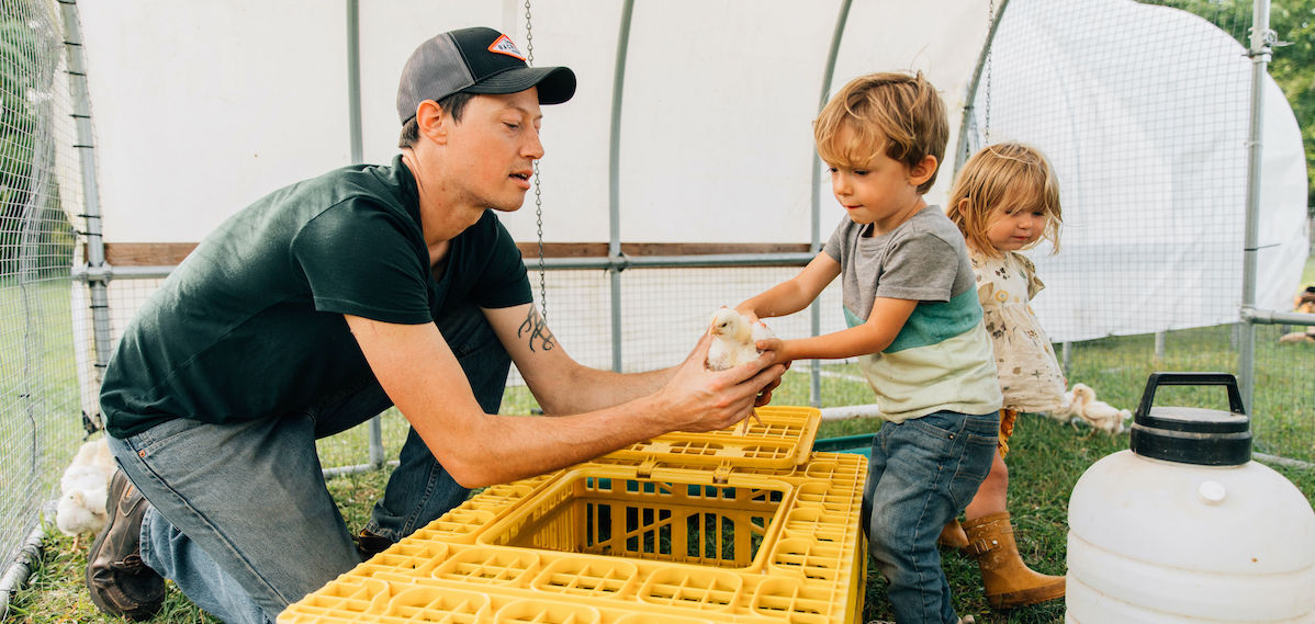 farmer letting homeschool students hold chickens