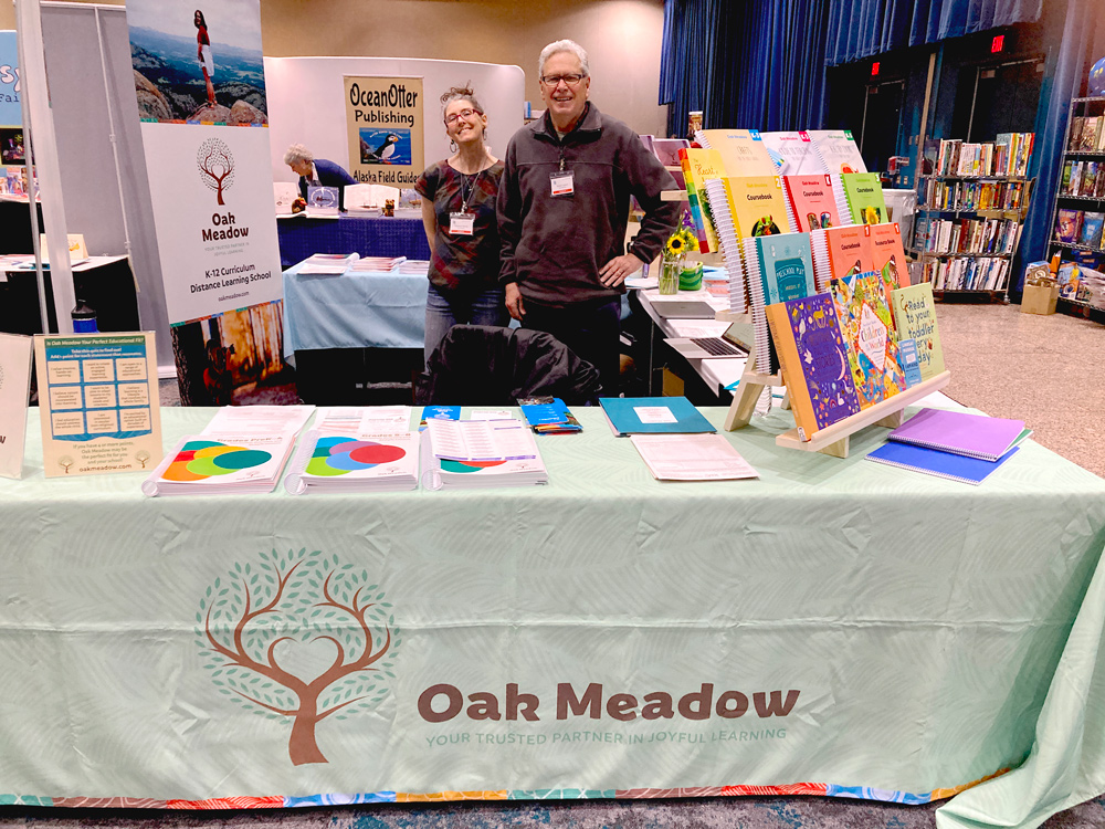 Oak Meadow staff members smile at homeschool conference booth