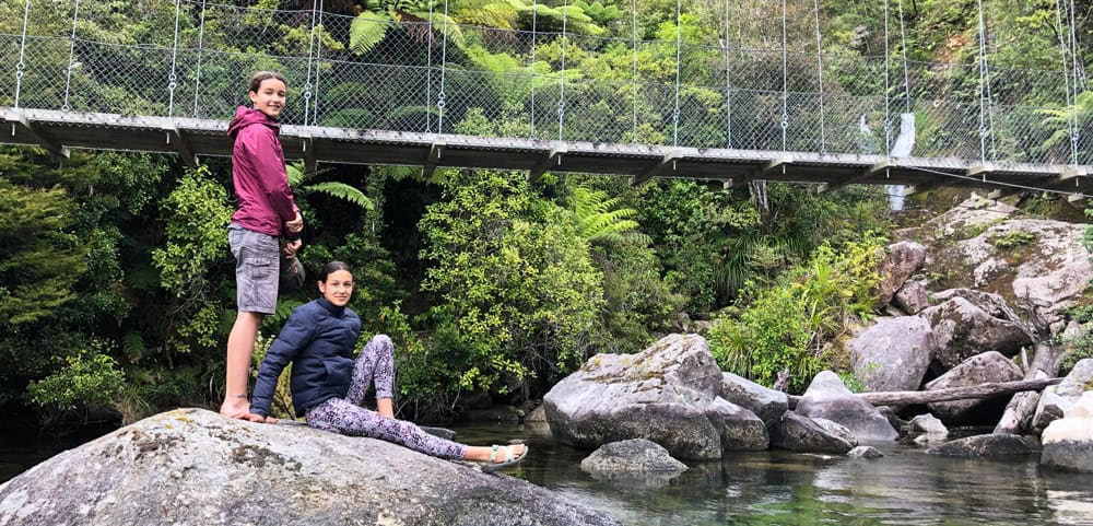 sisters sitting on a rock by a river