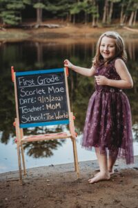 student taking back to school photo with cute chalkboard sign